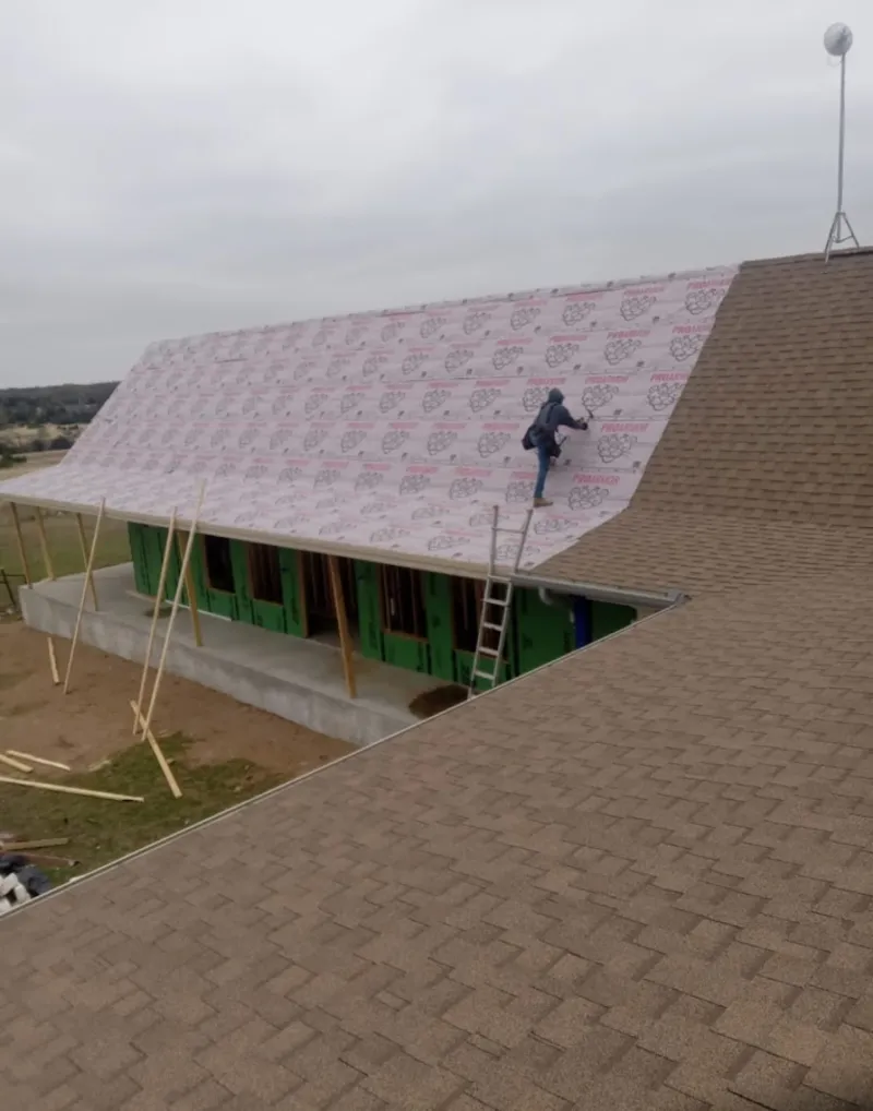 Worker preparing underlayment for a metal roof installation in Muskegon Heights